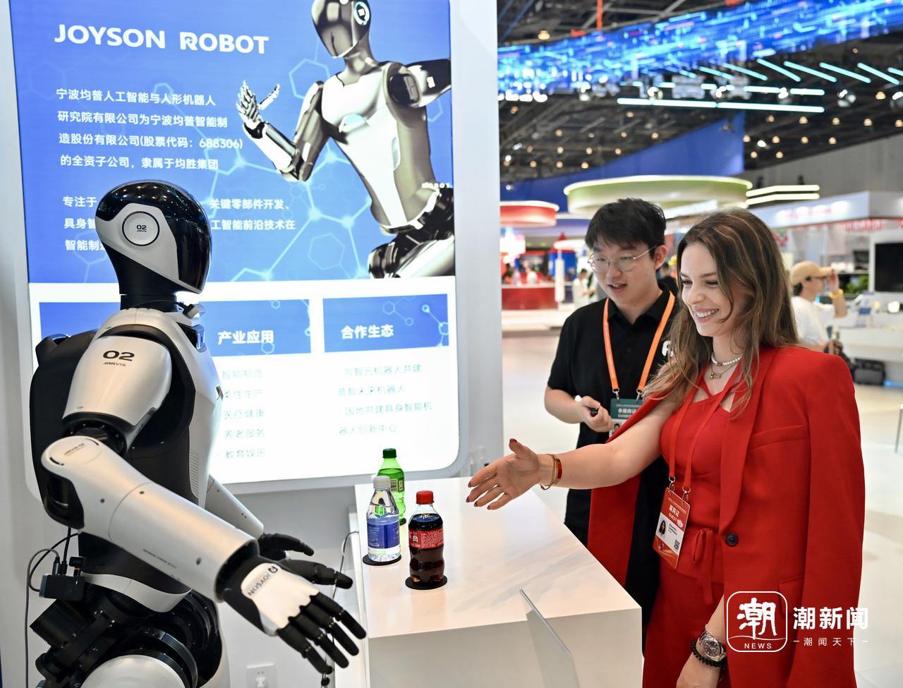 在数智中东欧展区,一位外宾伸手与中国产的人形机器人互动。.jpeg